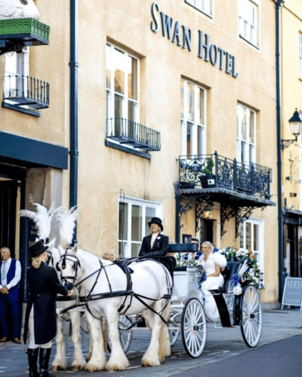 bride and groom in horse drawn carriage outside hotel